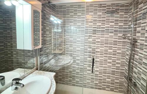 a bathroom with a sink and a glass shower at Holibai Amieiro Apto amplio y luminoso cerca de la playa, Baiona in Baiona