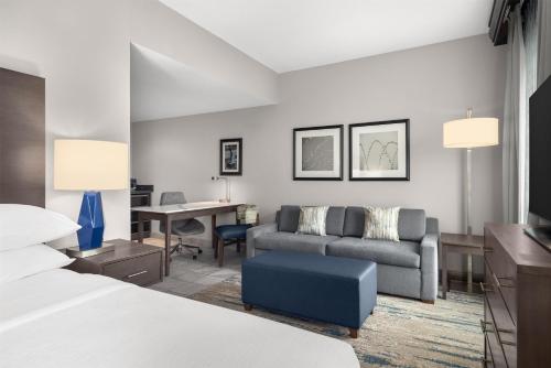 a hotel room with a bed and a couch and a desk at Embassy Suites Charlotte/Ayrsley in Charlotte