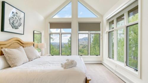 a bedroom with a large white bed with windows at Emerald Elk at Village Creek by AvantStay Close to Slopes Village w Views in Telluride