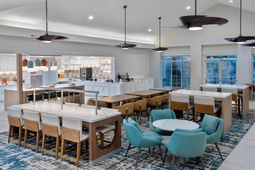 a dining room with tables and chairs and a kitchen at Homewood Suites by Hilton Orlando-Nearest to Universal Studios in Orlando