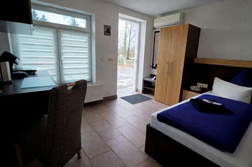 a bedroom with a desk and a bed with a blue blanket at Pension Schwarze Pumpe in Spremberg