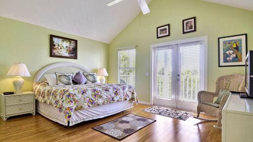 a bedroom with a bed and a chair and windows at Duval Breeze by AvantStay Great Location Close to Beach Nightlife Shared Pool Week Long Stays in Key West