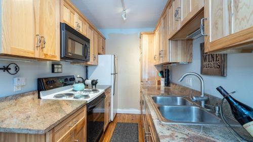 a kitchen with wooden cabinets and a sink and a refrigerator at Viking Lodge 103 by AvantStay Stunning Condo Near Ski Lift in Telluride