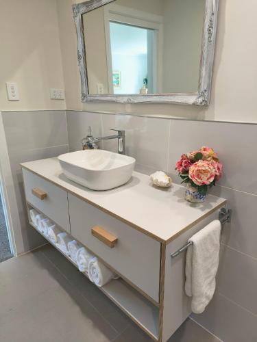 a bathroom with a sink and a mirror at Among The Tuii in Katikati