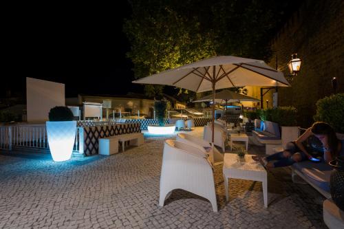 a group of chairs and umbrellas on a patio at night at Josefa D`Obidos Hotel in Óbidos