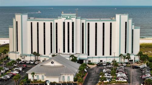 a large white building with cars parked in a parking lot at The Island House Hotel a Doubletree by Hilton in Orange Beach
