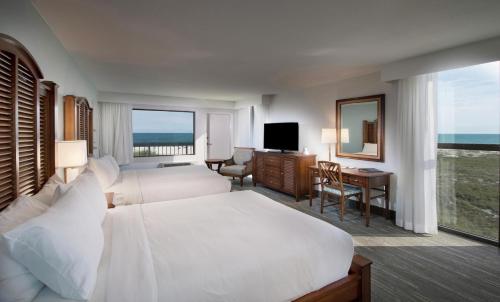 a hotel room with two beds and a desk at The Island House Hotel a Doubletree by Hilton in Orange Beach