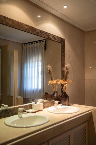 a bathroom with two sinks and a large mirror at Montesión 71 - Casa con piscina & jardín, al lado de Puy du Fou in Toledo