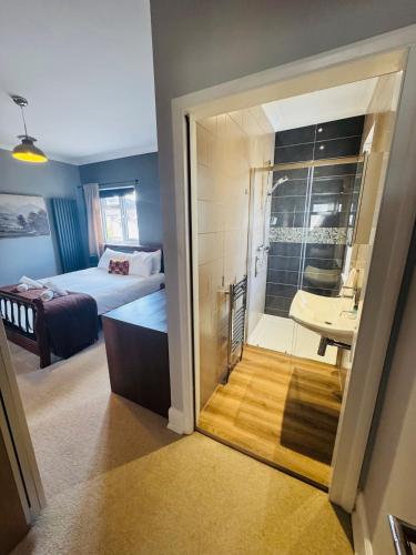 a bedroom with a bed and a bathroom with a sink at Mayors House Ideal for Groups & Business in Peterborough