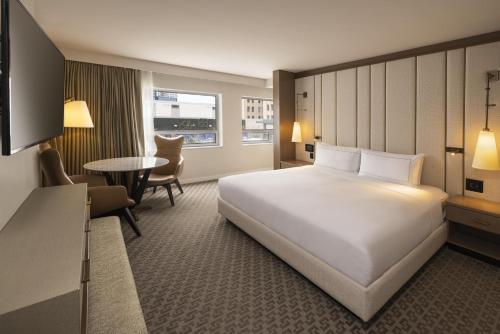 a hotel room with a large white bed and a table at The Statler Dallas, Curio Collection By Hilton in Dallas