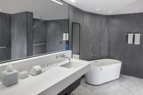 a bathroom with a sink and a tub and a mirror at The Statler Dallas, Curio Collection By Hilton in Dallas