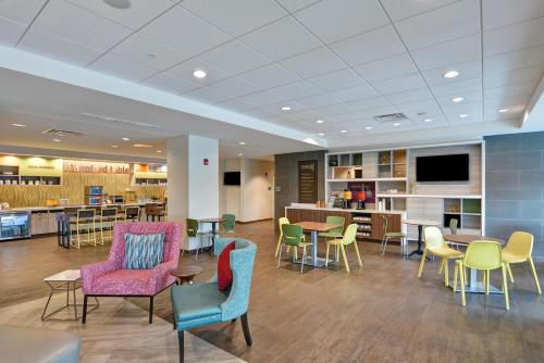 a waiting room with chairs and tables and a tv at Home2 Suites By Hilton Tampa USF Near Busch Gardens in Tampa