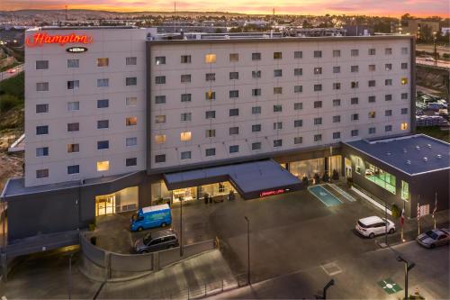 a large white building with a blue truck parked in a parking lot at Hampton Inn By Hilton Tijuana in Tijuana