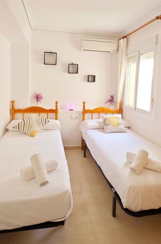 two beds in a room with white walls and windows at Casa Mediterránea Kai in Gran Alacant