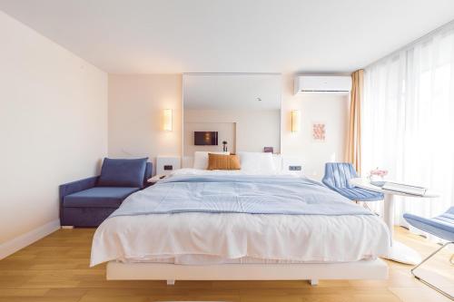 a bedroom with a large bed and a blue chair at Panorama Black Sea View Sunset Hotel in Batumi