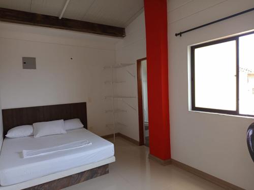 a bedroom with a white bed and a window at HOTEL CASCADA PLAZA in Santa Fe de Antioquia