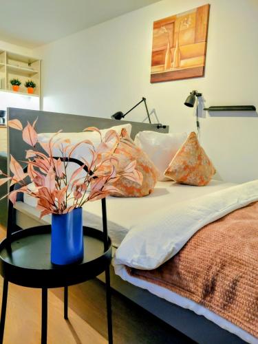a bed with a blue vase with flowers on a table at Langenfeld City Apartment in Langenfeld