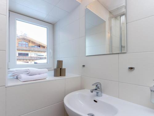 a white bathroom with a sink and a window at Golden Hirsch in Rauris