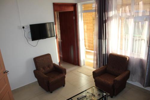 a living room with two chairs and a television at Bano Tourist Residence - 650 meters from Grand Bay Beach in Grand-Baie