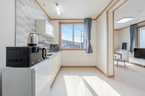 a kitchen with white cabinets and a microwave at Yeosu Turtleship Pension in Yeosu