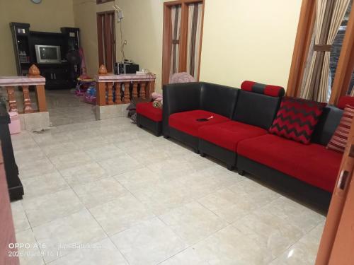 a living room with a red couch and a tile floor at Jupe Homestay batukaras in Batukaras