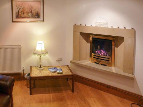 a living room with a fireplace and a table at Hollin Bank Cottage in Salterforth