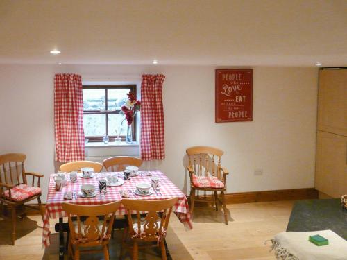 a dining room with a table and chairs and a window at Hollin Bank Cottage in Salterforth