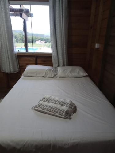 a bed with a towel on it with a window at Recanto do sol in Imaruí