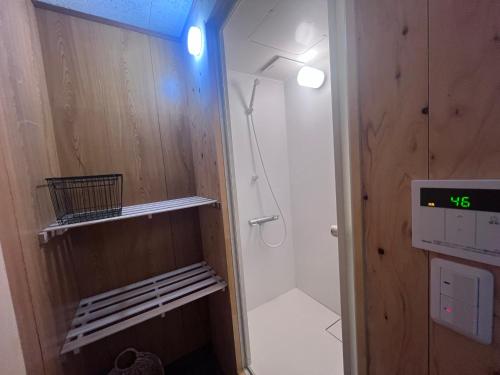 a bathroom with a shower and a clock on the wall at Hillshouse2はなれ in Tokoname