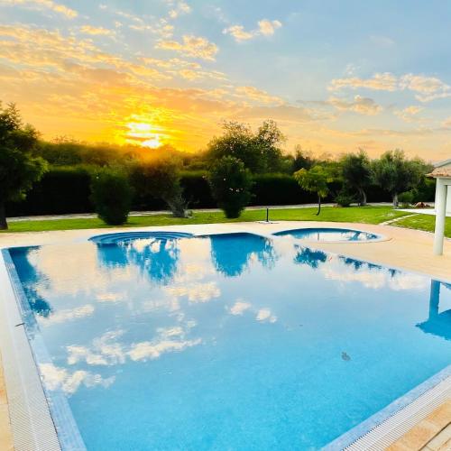 a large swimming pool with a sunset in the background at Olive Villa in Alcantarilha