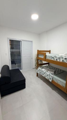 a room with two bunk beds and a couch at Mar e Natureza 2 quartos 6 Pessoas Lazer in Bertioga