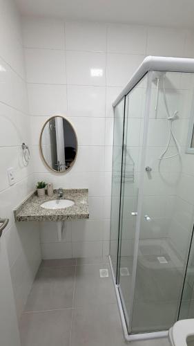 a white bathroom with a sink and a mirror at Mar e Natureza 2 quartos 6 Pessoas Lazer in Bertioga