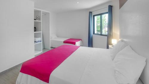a bedroom with a large white bed with a pink blanket at Valentina Suites by Las Flores Vacation Rentals in Playa del Carmen