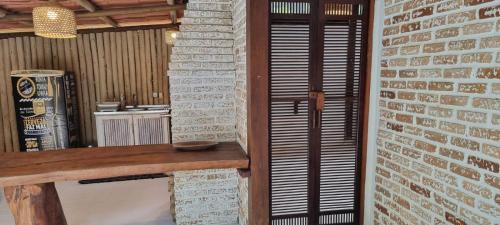 a room with a brick wall and a wooden table at Casa Irmã Lua in Porto Seguro