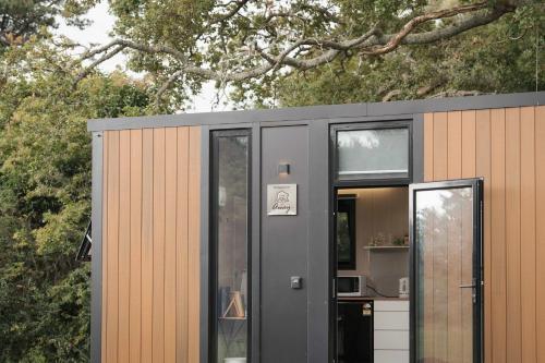 a small house with a gray door and windows at Sweet Hart 2 by Tiny Away in Tamahere
