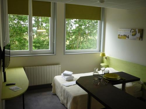 a hotel room with a bed and two windows at West Appart' Hôtel in Bessines