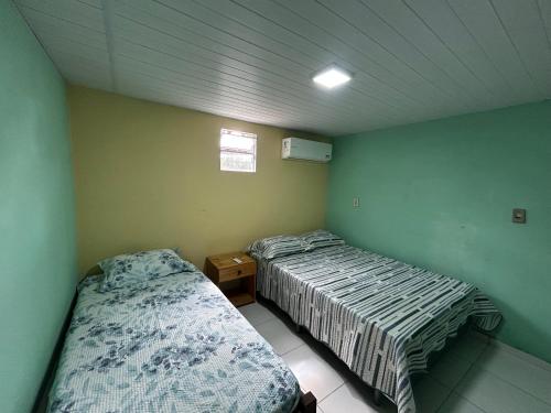 two beds in a room with green walls at Quarto Sairé in Santarém