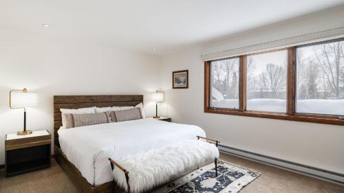 a white bedroom with a large bed and windows at Riverside Condos C202 by AvantStay Condo Close To Downtown Town Park Ski Lift 8 in Telluride