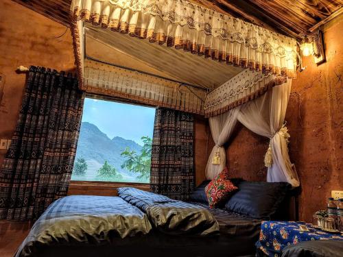 a bedroom with a canopy bed with a window at LÝ GIA HOMESTAY in Ha Giang
