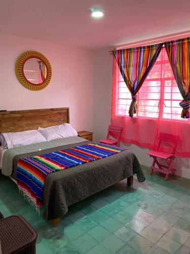 a bedroom with a bed and two red chairs at Casa Girasoles in Orizaba
