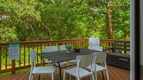 a black table and chairs on a deck with trees at For Lake Sake by AvantStay Lakefront Hot Tub View in Long Pond