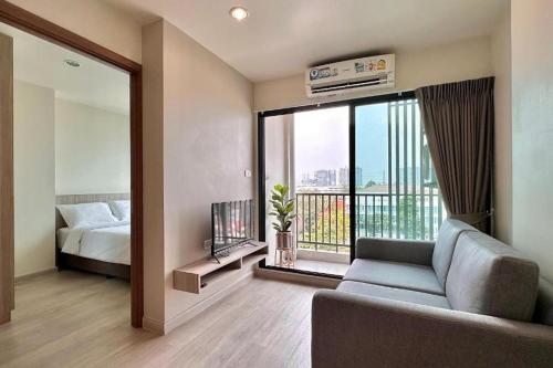 a living room with a couch and a bed and a window at The View Chaengwattana 14 in Bangkok
