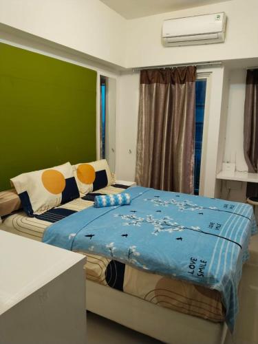 a bedroom with a bed with a blue blanket on it at Tanglin Tower with Netfix by AquHome in Surabaya