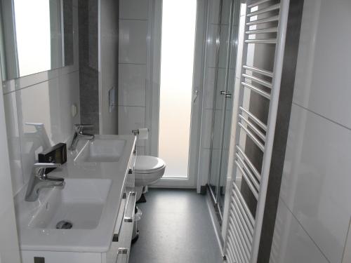a white bathroom with a sink and a toilet at Bemelen Holiday Home for 6 in Bemelen