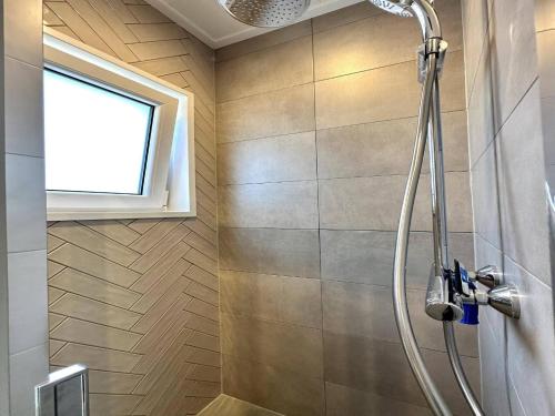 a shower in a bathroom with a window at Nature Park Chalet in Hoenderloo in Hoenderloo
