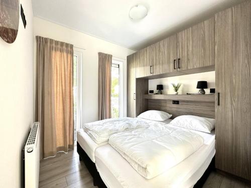 a bedroom with a large bed with white sheets at Nature Park Chalet in Hoenderloo in Hoenderloo