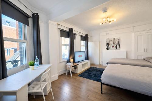 a bedroom with a bed and a desk with a computer at The Prestige Suite - London in London