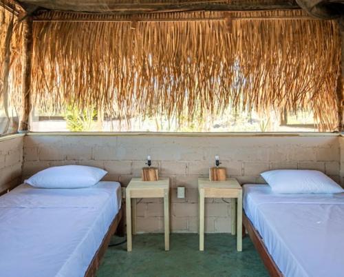 two beds in a room with two tables and a window at The Dream Eco Glamping in La Sabrosa
