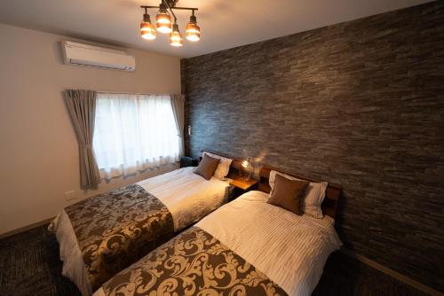 a bedroom with two beds and a brick wall at URADO TERRACE Private villa 無料駐車場4台 最大10名 桂浜近く ジャグジー シアタールーム完備 in Kochi