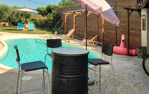 a pool with chairs and a table and an umbrella at Maison Avec Piscine in Salavas